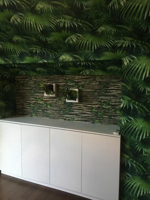 「スタイリッシュジャングル」　トレンドのボタニカル柄の壁紙を大胆に使い、密林の中に入り込んだかのようなトロピカルな世界に、相反するスタイリッシュな家具を組み合わせている。床置きだけでなく、天井から吊るしたり壁面を活用したり、都会でもできるグリーンの活用方法がポイント。